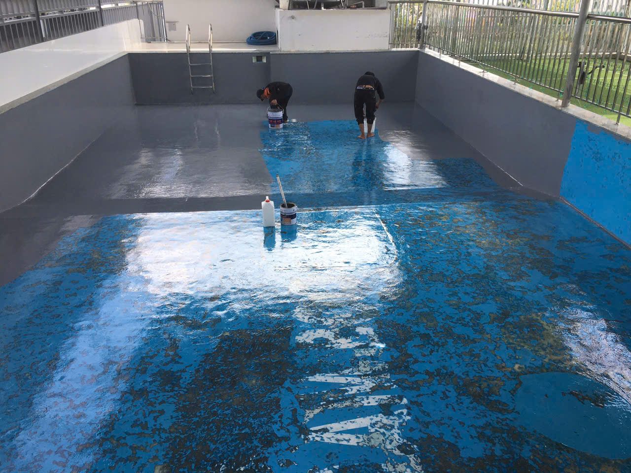Đội thi công Sơn Công Nghiệp đang cải tạo hồ bơi bị bong tróc - thi công lớp epoxy xám mới lên nền sơn xanh cũ đã được xử lý