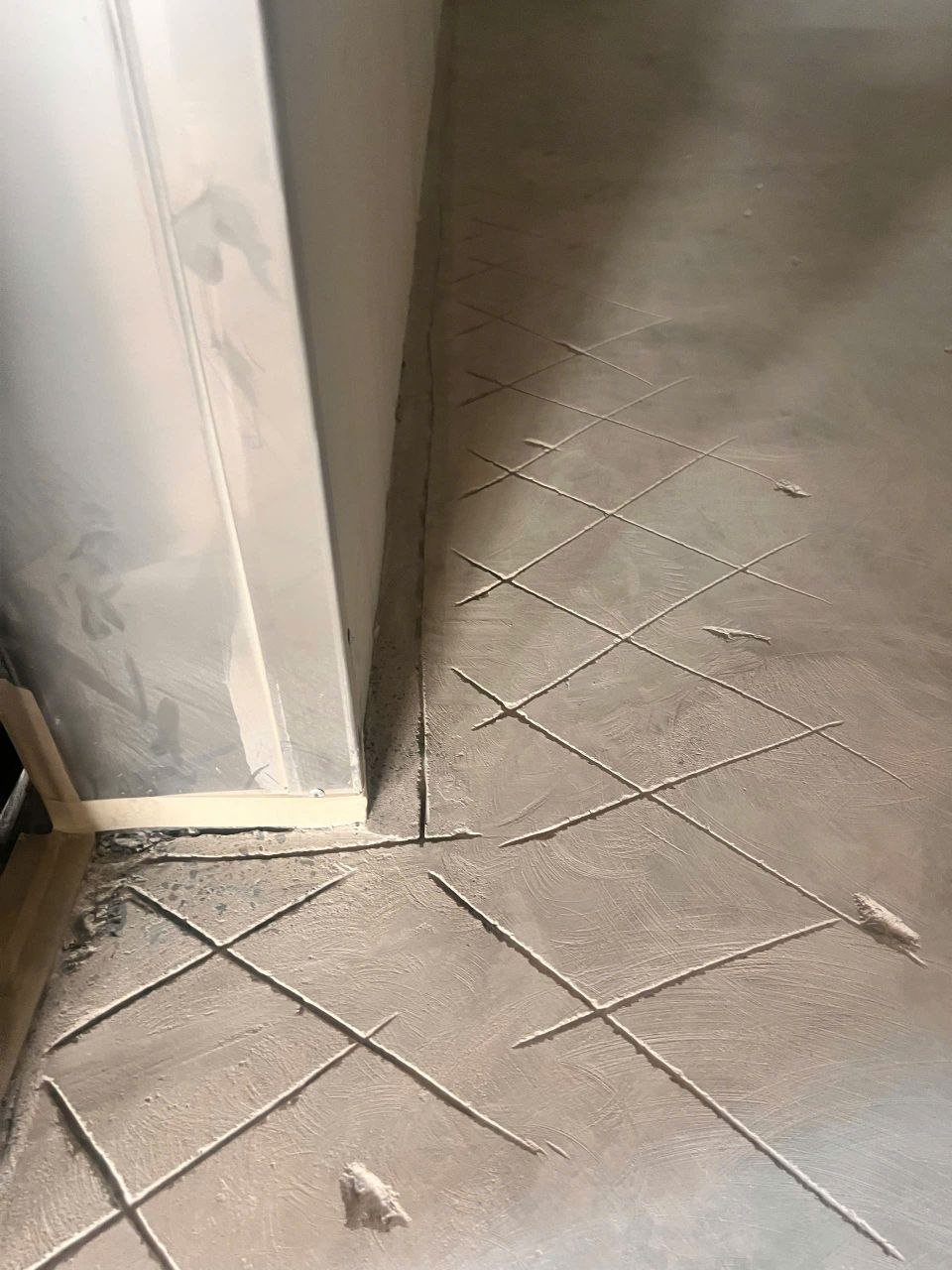 Cận cảnh rãnh ngàm cắt dọc chân tường và các đường khía chéo tạo nhám trước khi thi công vữa PU