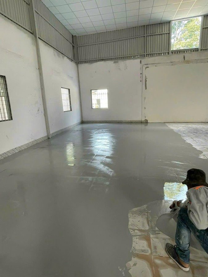 Thi công sơn epoxy tự san phẳng trên nền gạch men nhà xưởng – người thợ đang lăn sơn