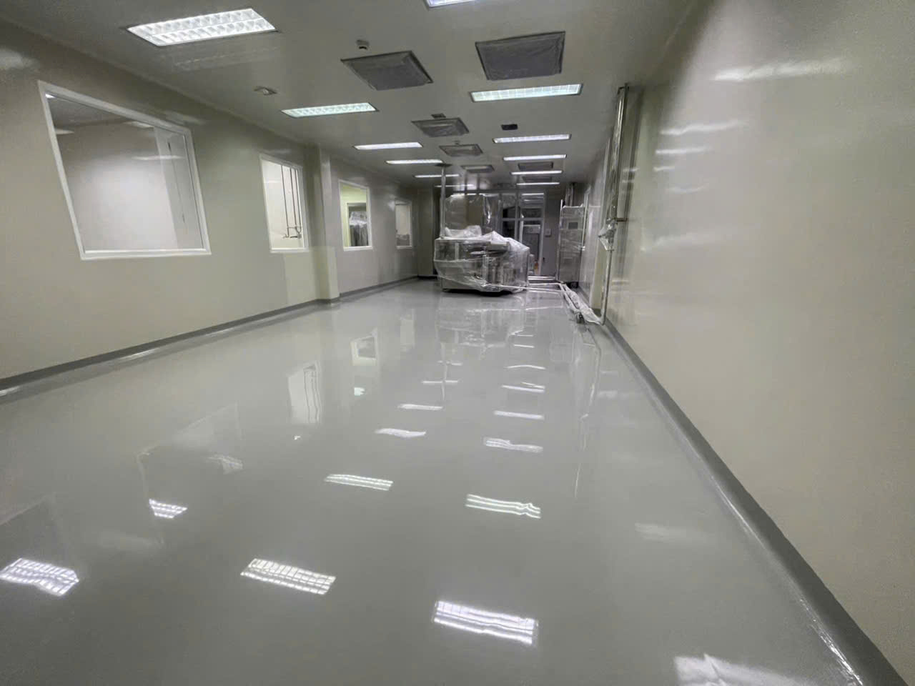 Hành lang phòng sạch với sàn tự phẳng bóng, bo chân tường và hệ lọc khí trên trần