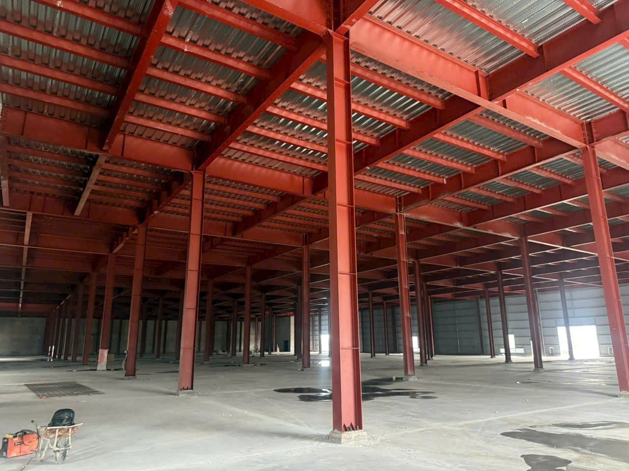 Kết cấu thép sơn lót đỏ bên trong nhà xưởng đã hoàn thiện mái và tường bao