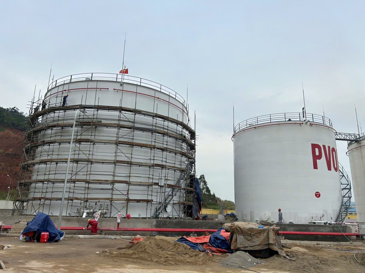 Công trình thi công sơn bồn chứa sắt thép công nghiệp PVOIL - bồn thép mới dựng giàn giáo bên cạnh bồn đã hoàn thiện sơn phủ trắng