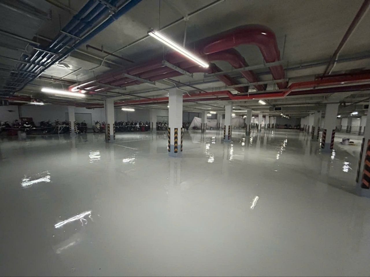 Bãi đỗ xe máy tầng hầm hoàn thiện sơn epoxy màu xám bóng - cột sơn cảnh báo vàng đen, hệ thống PCCC màu đỏ